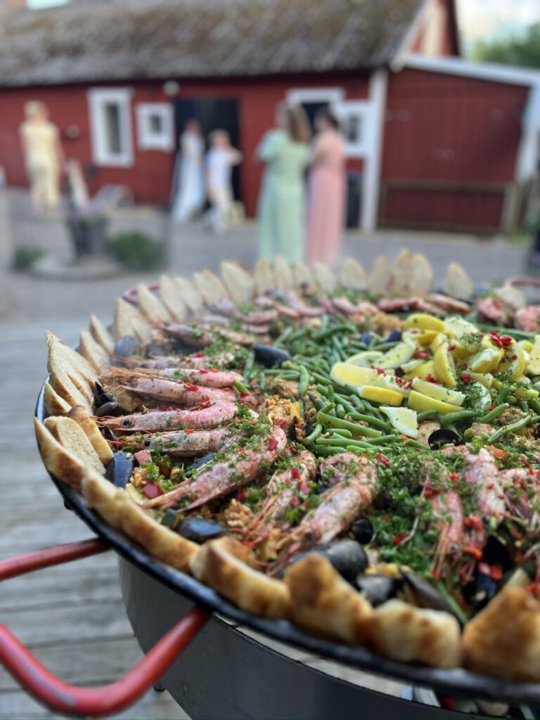 Paellapanna framför röda stugor